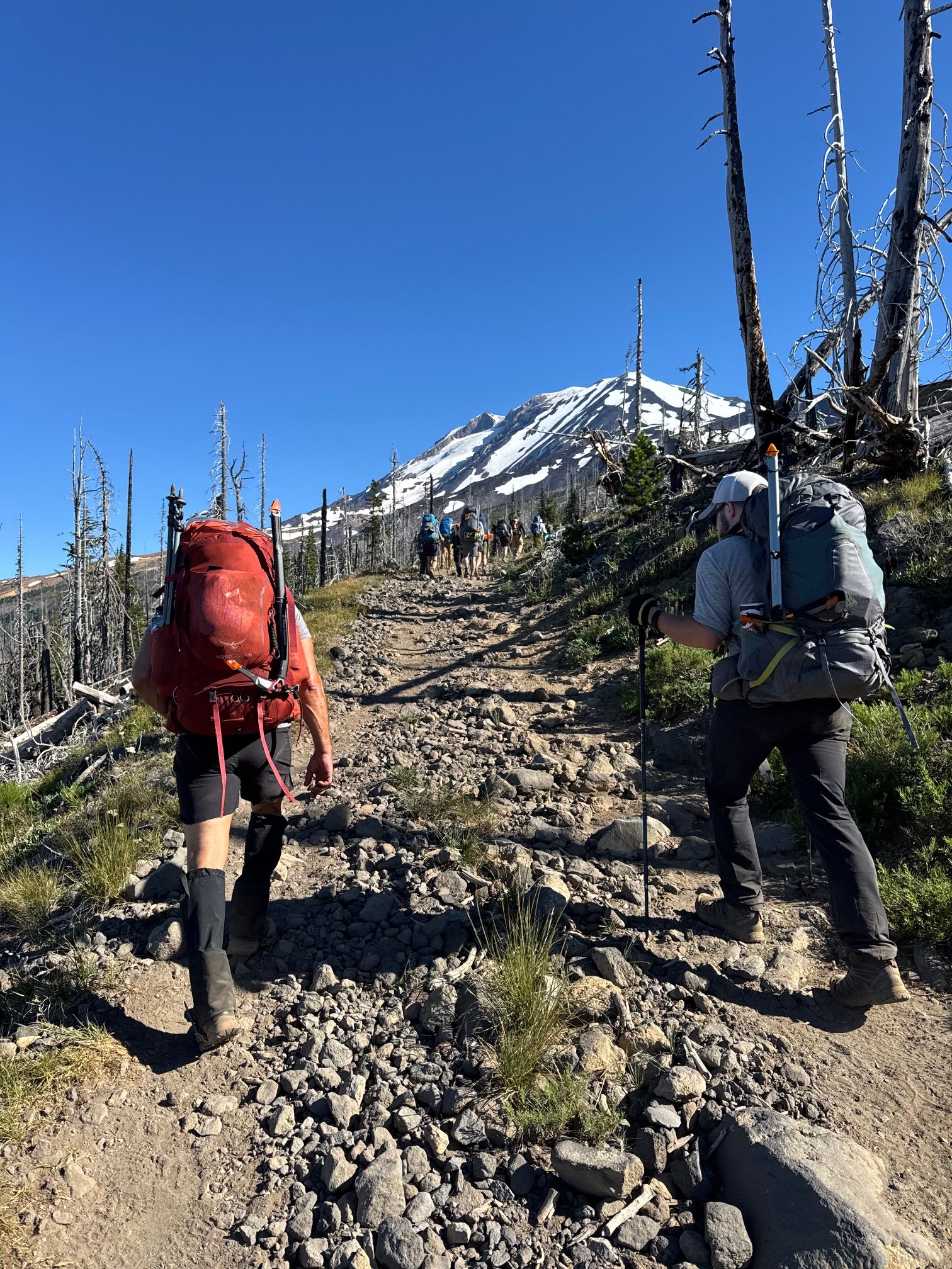 Climbers ascending a rocky trail on Mt. Adams with the snow-covered peak visible ahead